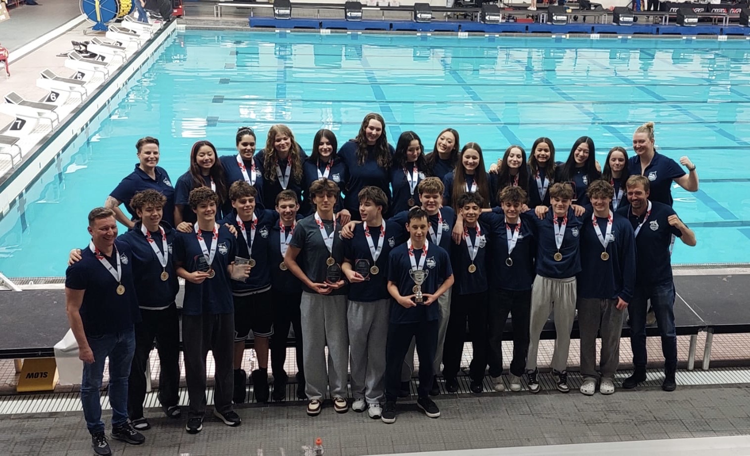 Surrey Water Polo competitive team with medals and trophies beside the competition pool